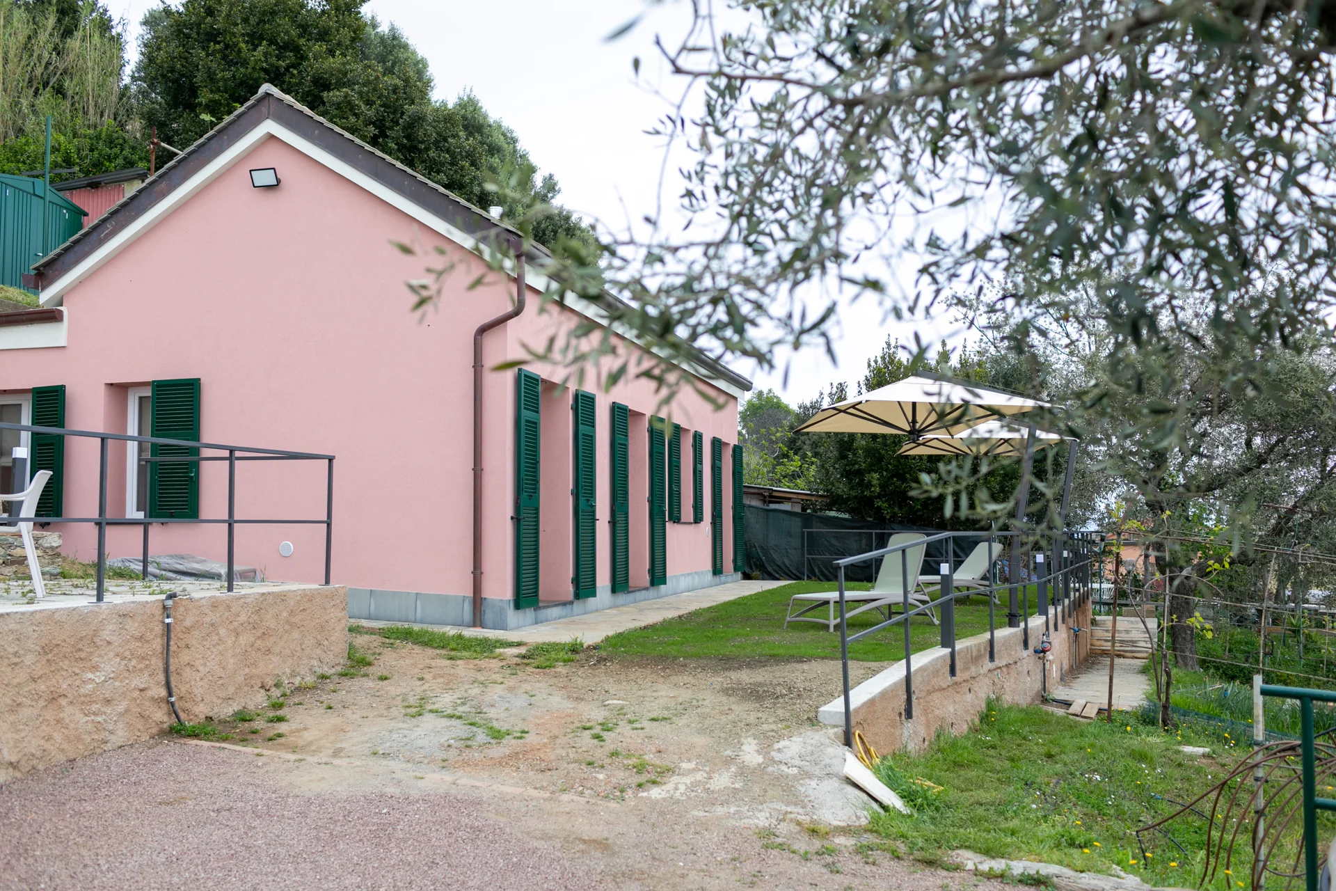 La facciata rosa con persiane verdi e giardino